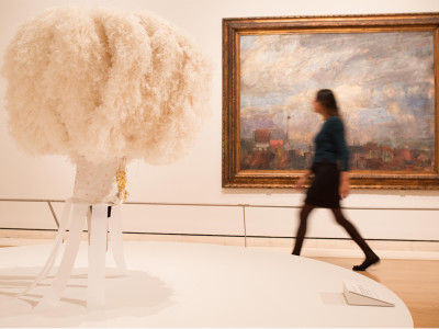 Installation image of the Intrigue: James Ensor by Luc Tuymans exhibition showing Ostrich feather headdress worn by the Gilles de Binche on the morning of Shrove Tuesday in the foreground, and Large View of Ostend (Rooftops of Ostend) by Ensor, 1884, in t