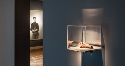 Installation shot shows: 'The Hand', 2012, Traditional casting wax and flock base artwork, Courtesy the artist and Maureen Paley, London AND 'Me as Arbus', 2008, Bromide afdruk | Bromide print, Collectie De Hallen, Courtesy the artist and Maureen Paley, L