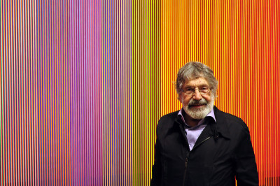 Carlos Cruz-Diez photographed in front of his work 'Physichromie no. 500' in the RA exhibition 'Radical Geometry'
