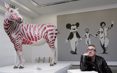 Damien Hirst with 'Stripped (Instinctual) by Michael Joo (left), and 'Can't beat the feeling' by Banksy (right), both from his murderme collection
