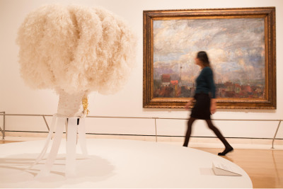 Installation image of the Intrigue: James Ensor by Luc Tuymans exhibition showing Ostrich feather headdress worn by the Gilles de Binche on the morning of Shrove Tuesday in the foreground, and Large View of Ostend (Rooftops of Ostend) by Ensor, 1884, in t