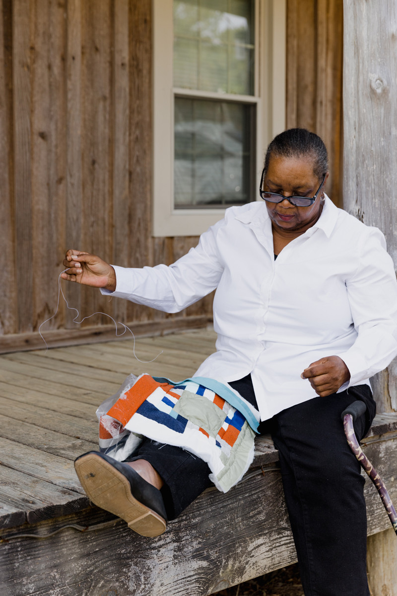 Mary Margaret Pettway sewing her quilt on the porch