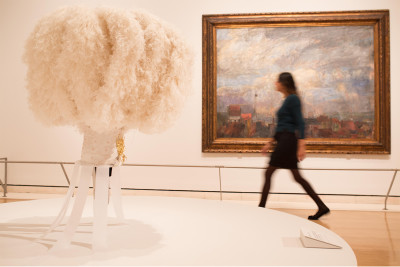 Installation image of the Intrigue: James Ensor by Luc Tuymans exhibition showing Ostrich feather headdress worn by the Gilles de Binche on the morning of Shrove Tuesday in the foreground, and Large View of Ostend (Rooftops of Ostend) by Ensor, 1884, in t